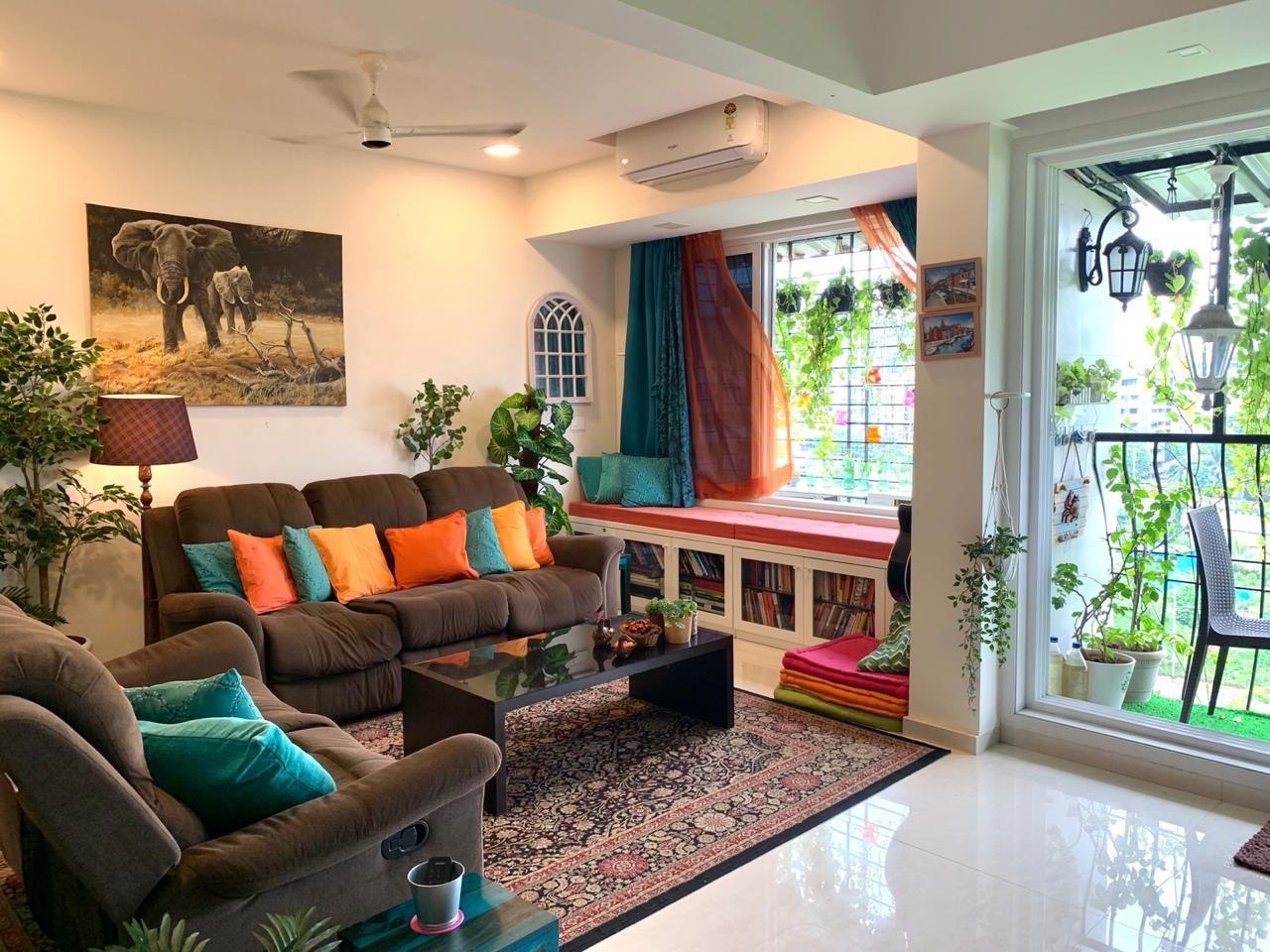 The Happiness Studio set up for a circle: window seat with cushions, sofa, plants, books, guitar - a warm room ready to hold a group