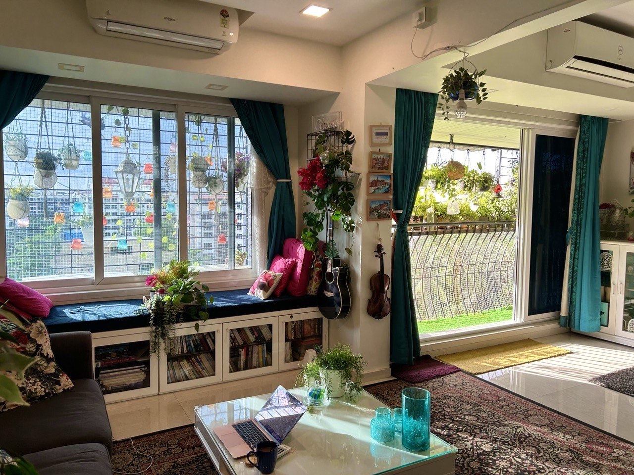 The Happiness Studio window seat with hanging coloured lanterns, bougainvillea, plants, and a deep cushion - daylight pouring in